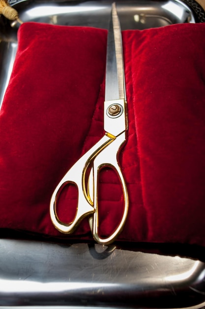 Позолоченные ножницы на красной подушке для перерезания ленты на церемонии открытия