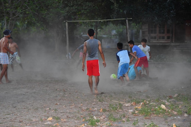 GILI ASAHAN, INDONESIA - AUGUST, 22 2016 - boys are playing soccer at sunset on a palm tree field near the beach