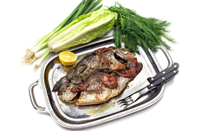 The gilthead bream Sparus aurata with vegetables on a plate closeup