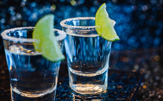 Фото Джин или водка с лаймом. два стакана с коктейлем алкоголя с лимонами на черной синей поверхности. водка, коктейль, алкоголь, напитки, ресторан, концепция релаксации.