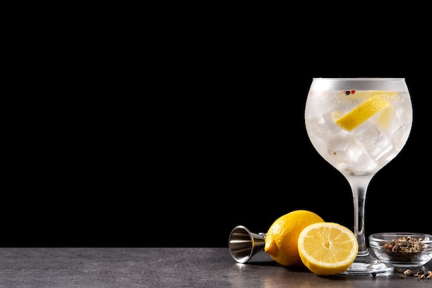 Gin tonic cocktail drink into a glass on black background Copy space