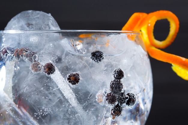 Foto primo piano a macroistruzione del cocktail tonico del gin con le bacche di ginepro