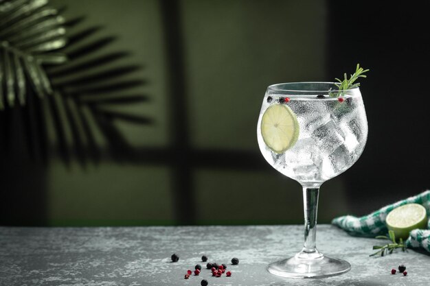 Photo gin tonic cocktail and shadows next to the window on dark concrete background