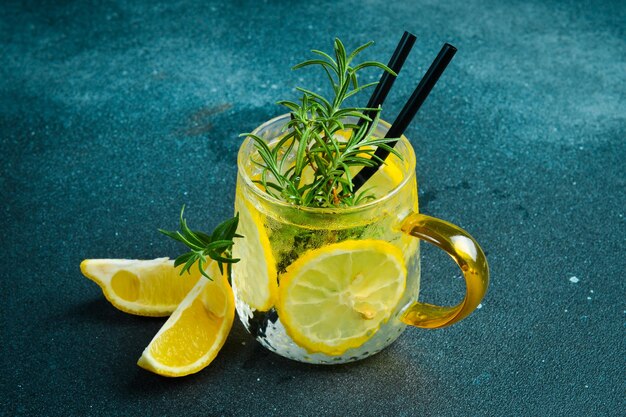 레몬과 로즈마린과 얼음으로 된 진 토닉 테일 어두운 돌 테이블에서 음료