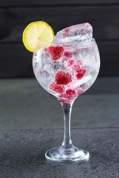 Gin tonic cocktail con fetta di lampone lima e ghiaccio