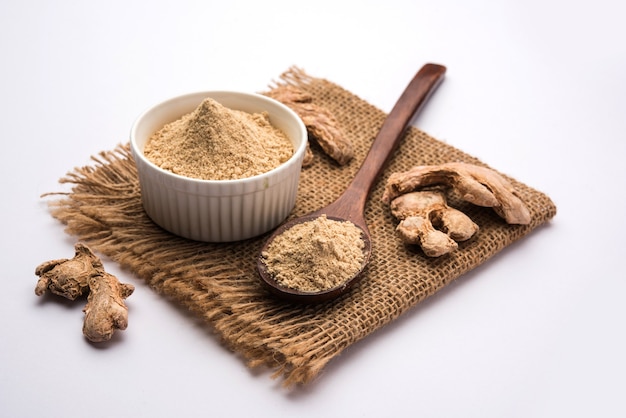 Ginger or Adrak powder with dried whole, also known as Sunth or Sonth in India, Over moody background. selective focus