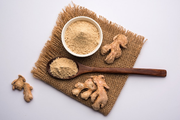 Ginger or Adrak powder with dried whole, also known as Sunth or Sonth in India, Over moody background. selective focus