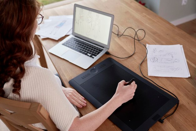 Photo ginger adult woman using laptop and designing a dress