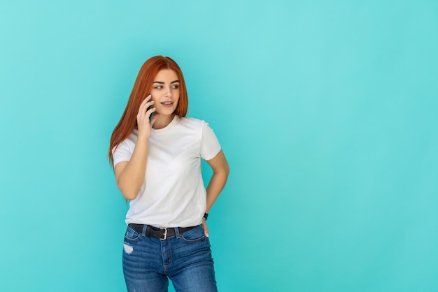 Ginger amazing woman posing isolated on turquoise wall holding folder talking by mobile phone.