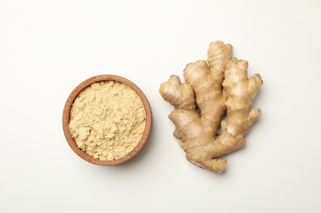 Ginger and bowl with ginger powder on white background