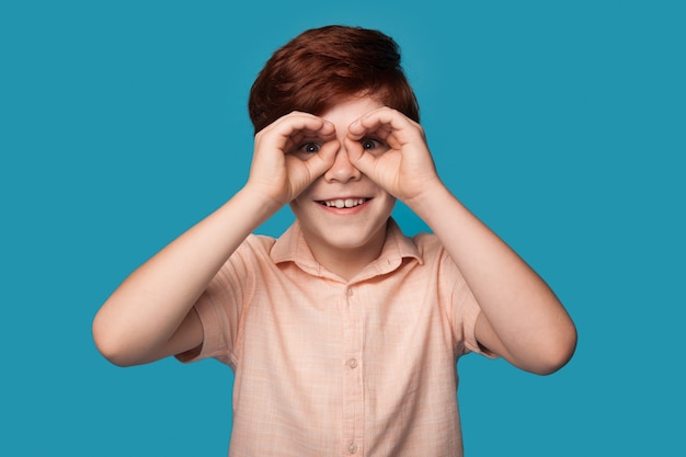 ginger boy is gesturing like having binoculars on eyes