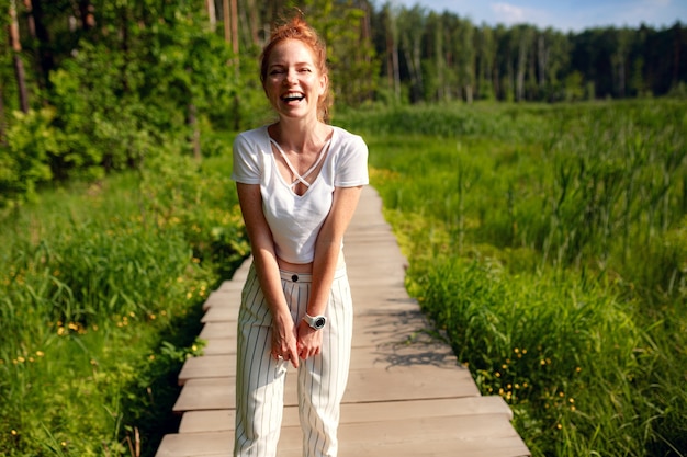 Ginger charming woman young beautiful forest green. Caucasian girl relaxing and enjoying life on nature outdoors.