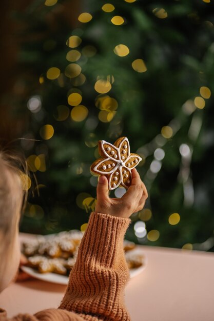 Photo ginger christmas cookies in childrens hands on the background of the christmas tree