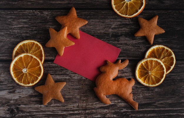 Ginger cookies in the form of deer and stars with orange slices on a wooden background