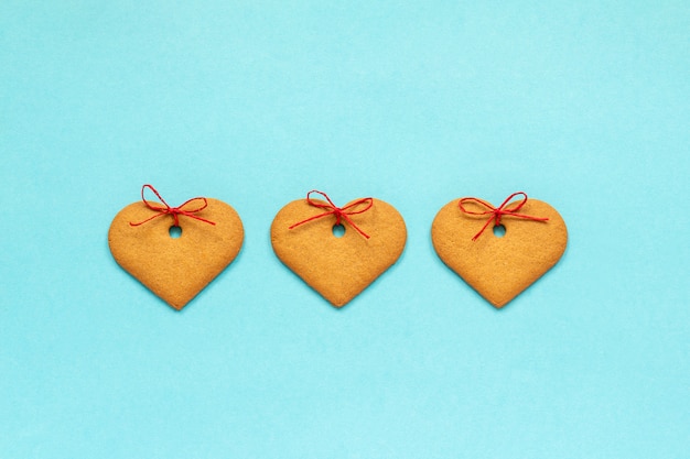 Ginger cookies heart-shaped decorated with a bow on blue background Valentine card