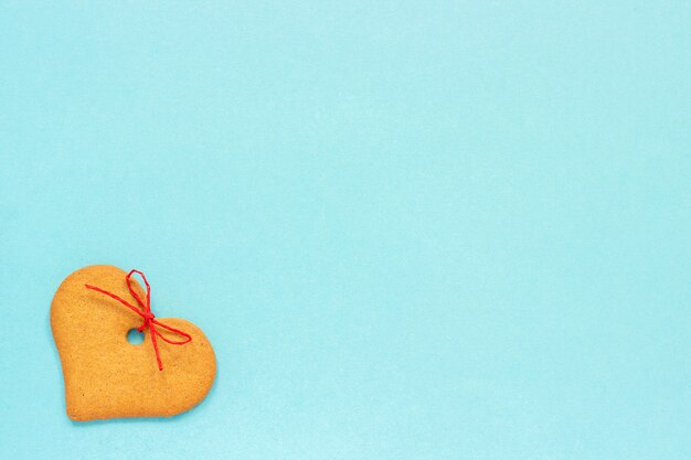 Ginger cookies heart-shaped decorated with a bow on a blue background.