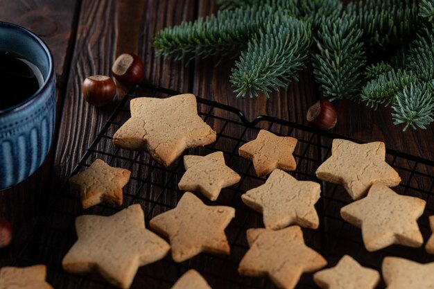 Ginger cookies in the shape of stars on the grill next to fir twigs and a mug of tea