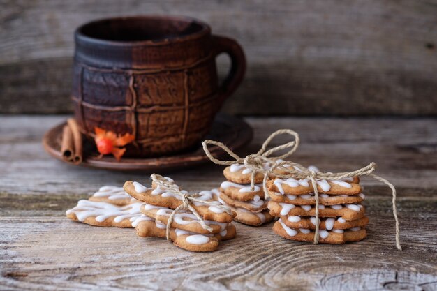 Biscotti allo zenzero con glassa fatta in casa e una grande tazza di caffè su un tavolo di legno