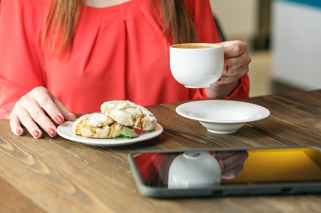테이블에 커피 컵 커피 브레이크 개념 태블릿을 들고 생강 쿠키와 여자 손