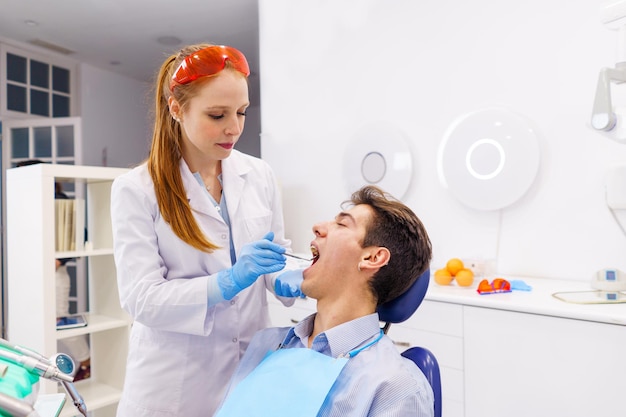 Ginger dentist examining teeth of male patient