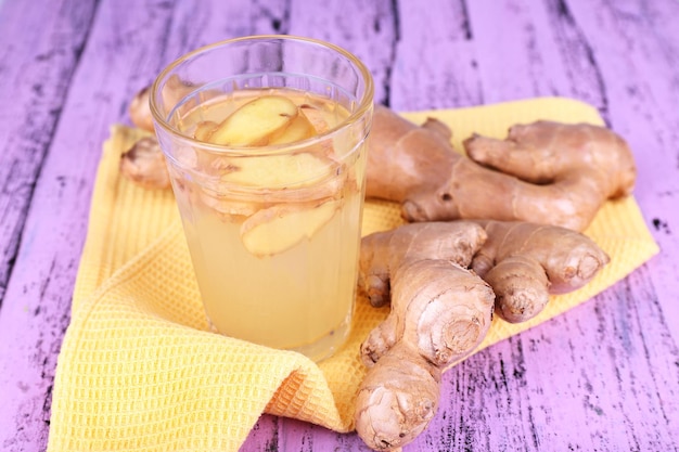 Photo ginger drink and ginger root on napkin on wooden background