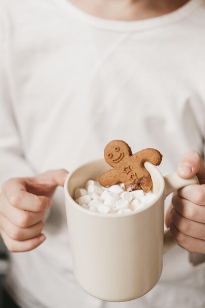 Ginger man in a cup of cocoa with a big red bow on a white background, top view. Various Christmas sweets with a cup of cocoa on the table.