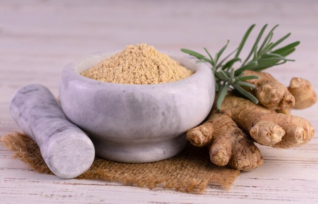 Ginger root and ginger powder in a stone mortar. Close-up