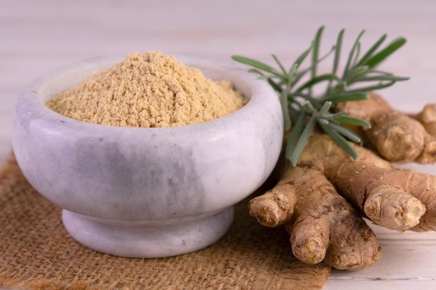 Ginger root and ginger powder in a stone mortar. Close-up