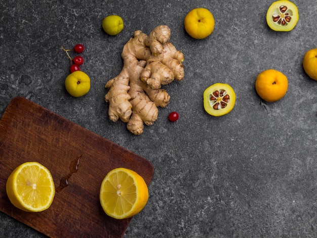 Ginger root lemon on wooden board cydonia red berries on grey background