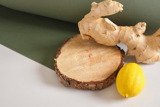 Ginger root, lemon and wooden stand on gray and green\
background, mock up cosmetic background