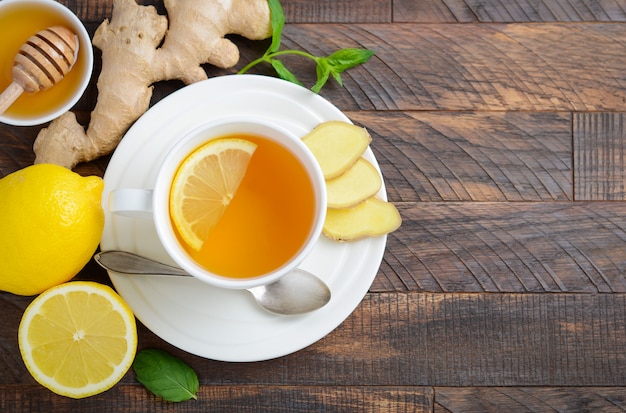 Ginger root tea with lemon and honey on wooden table, top view, copy space.