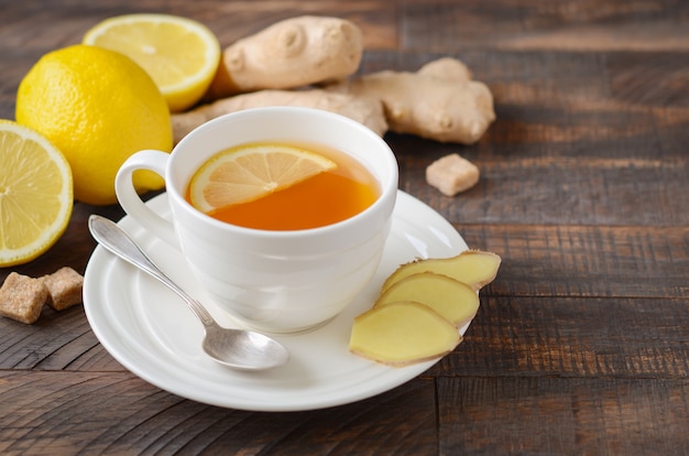 Ginger root tea with lemon and honey on wooden table.