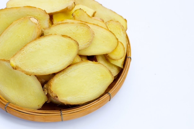 Ginger slices in bamboo basket on white background.