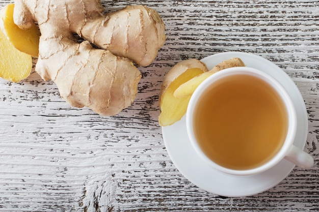 Ginger tea in a white cup on wooden background