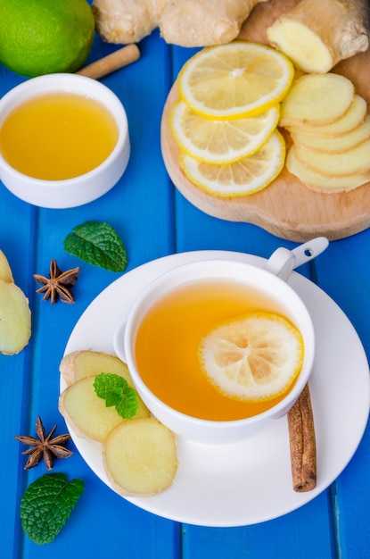 Ginger tea with lemon and honey on blue wooden background. Healthy drink.