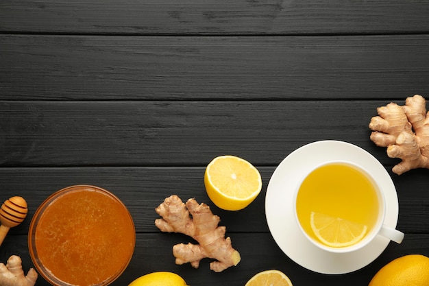 Ginger tea with lemon in a white cup on black background. Top view