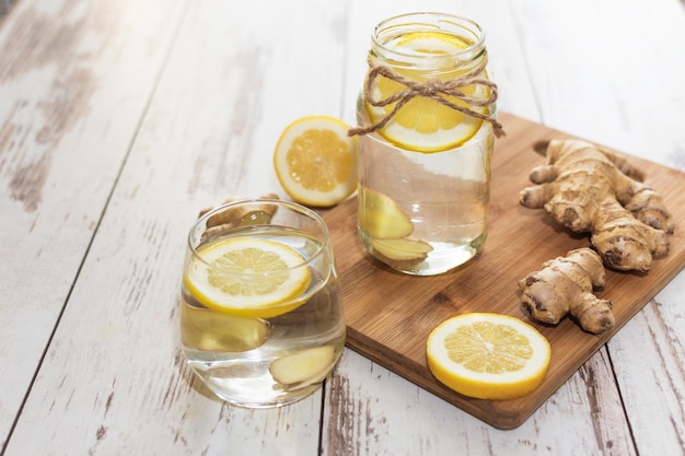 Photo ginger with lemon detox water in the morning on wooden background