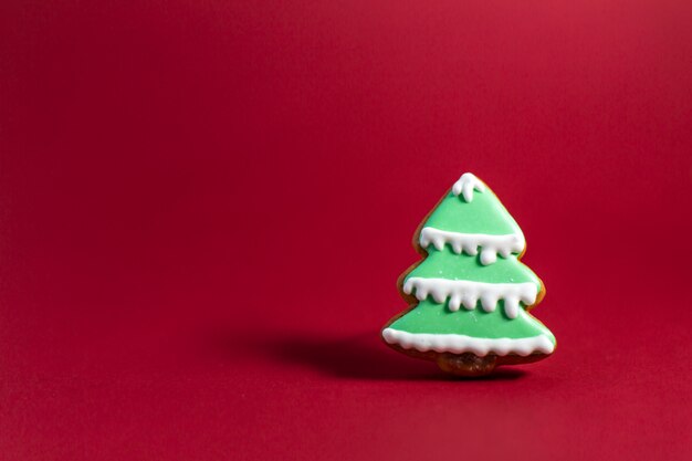 Gingerbread cookie of green Christmas Tree on red background. 