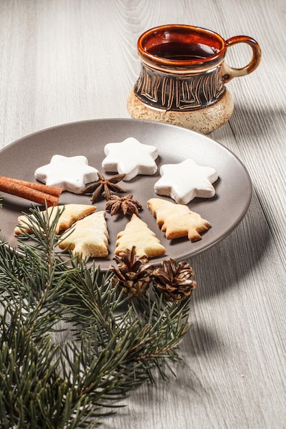 Gingerbread cookies in Christmas tree and star shape on plate with cup of coffee