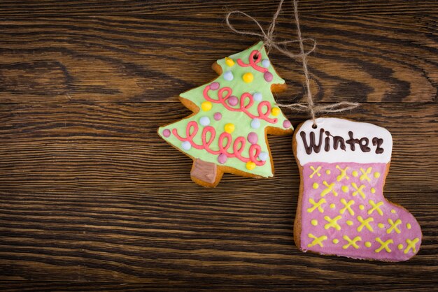 Gingerbread cookies hanging over wooden . Christmas decorations top view with copy space. Prepare for xmas eve or other winter holidays