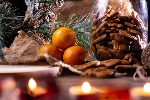 Gingerbread cookies in a jar. Mandarins create a New Year's mood. Festive lanterns in the foreground. All this against the backdrop of linen material.