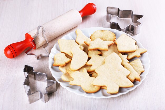 Gingerbread cookies on plate with copper cookie cutter and rolling pin on wooden table