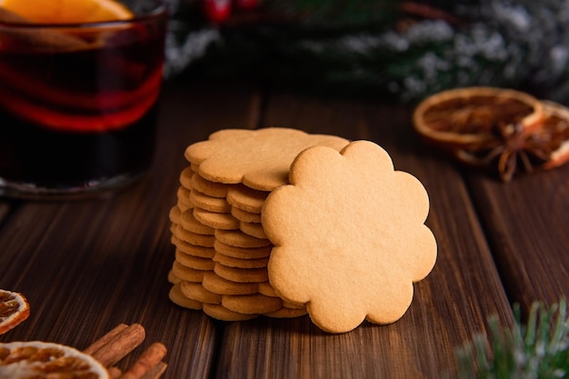 Gingerbread cookies in a stack with spices on a wooden background and spruce branches in the back
