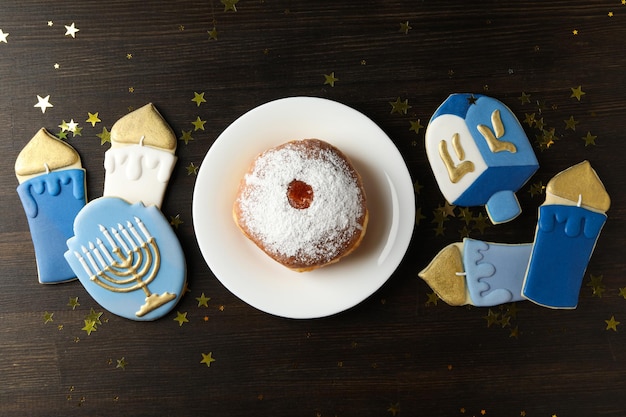 Gingerbread cookies with Jewish signs and donuts on wooden background top view