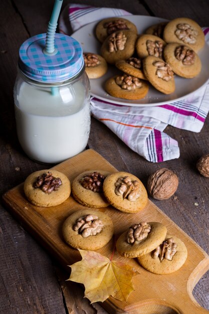 Gingerbread cookies with walnuts on a table and a cup of milk