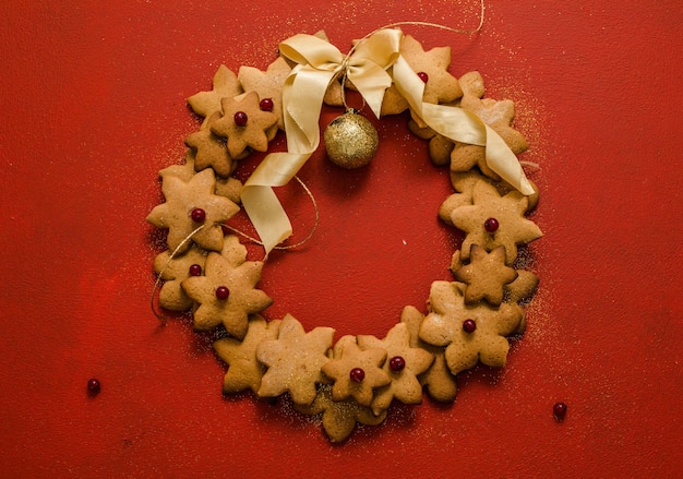 Photo gingerbread cookies wreath on red background, top view, copy space