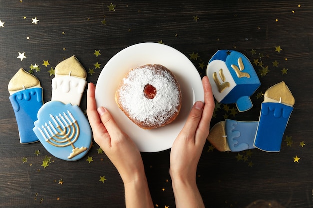 gingerbread donut on plate and female hands on wooden background top view