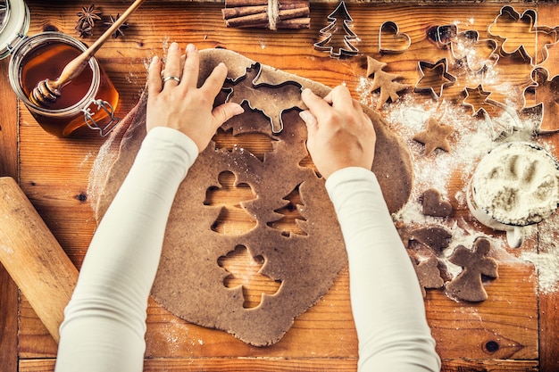 Gingerbread dough and woman hands preparing christmas biscuit cakes.