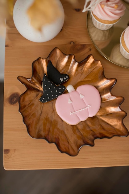 ピンクのカボチャと魔女の帽子の形をしたジンジャーブレッド、ハロウィーンの甘いテーブルの飾り。
