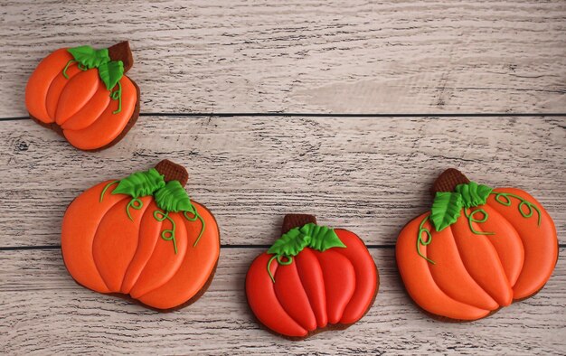 Gingerbread handpainted in the form of pumpkins on a light wooden background